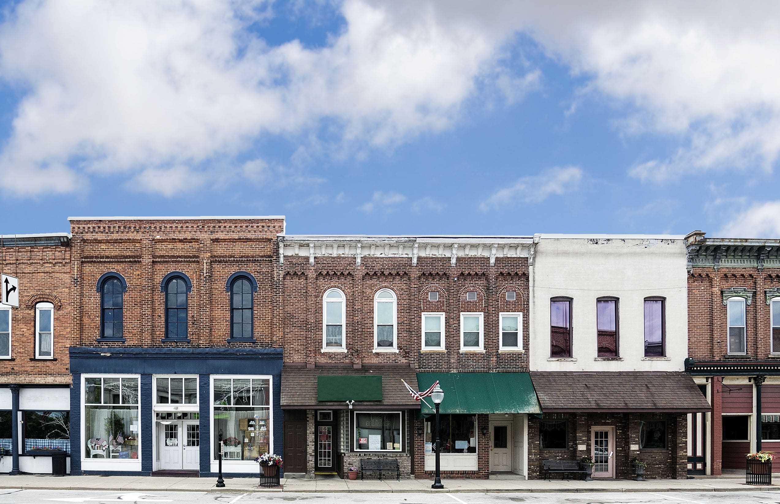 A photo of a typical small town main street in the united states of america features old brick buildings with specialty shops and restaurants decorated with spring flowers and american flags